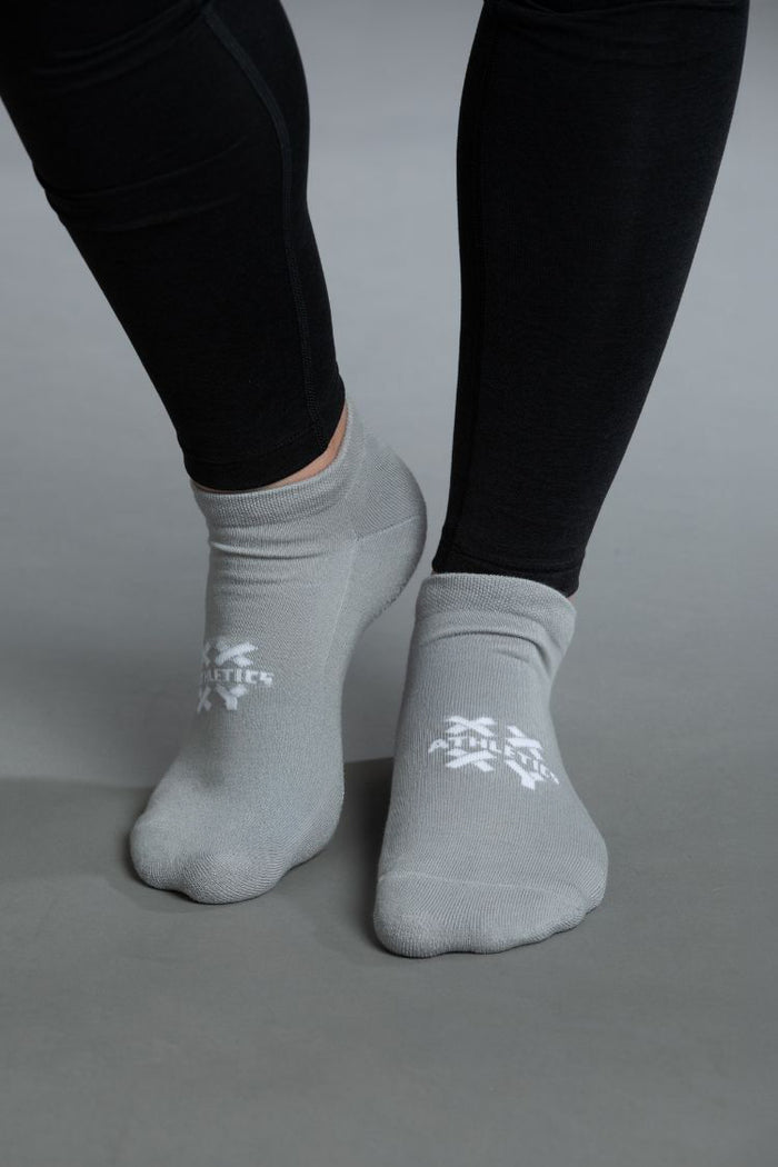 Gray socks with a logo worn by a person in black leggings on a gray background || gray