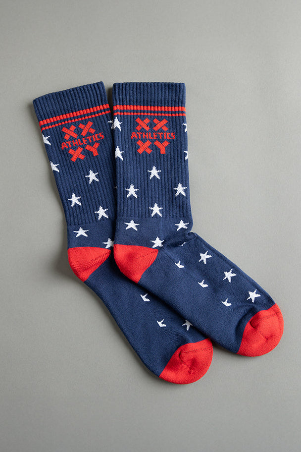 Pair of blue socks with red accents and white star patterns on a gray background || patriotic with stars