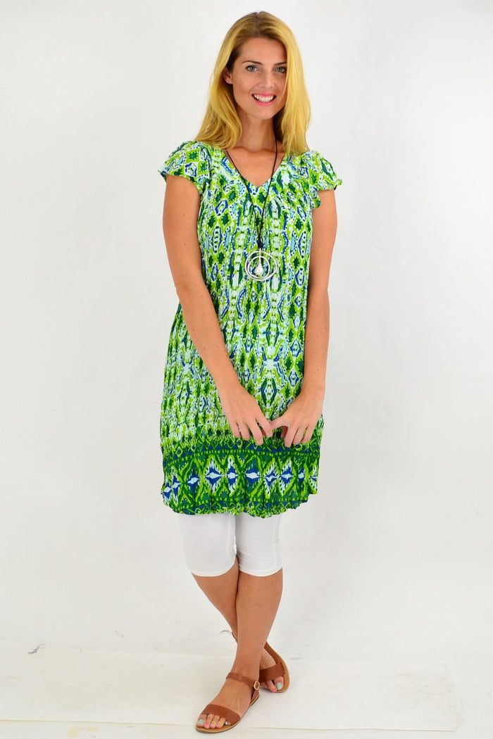 Green patterned short sleeve tunic dress by One Summer with a relaxed fit, displayed on a hanger against a plain background.
