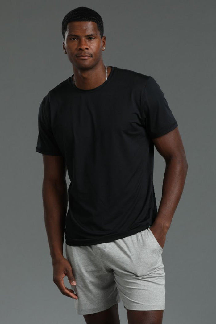 Man wearing a black t-shirt and light gray shorts on a gray background || Dark Heather Gray/Black