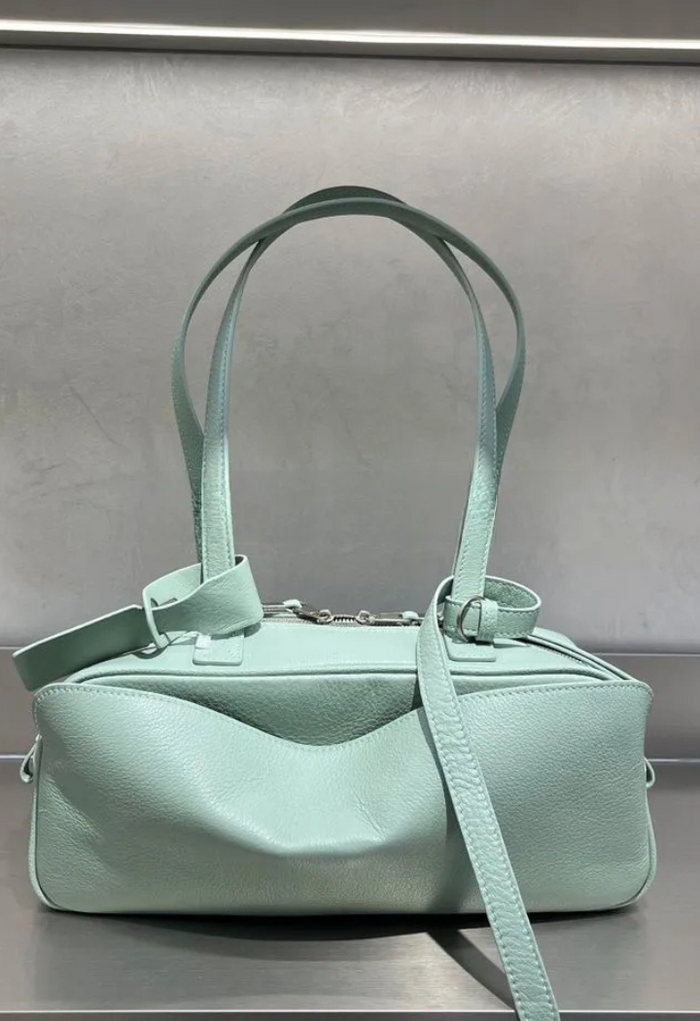 Mint green handbag with a strap on a gray background